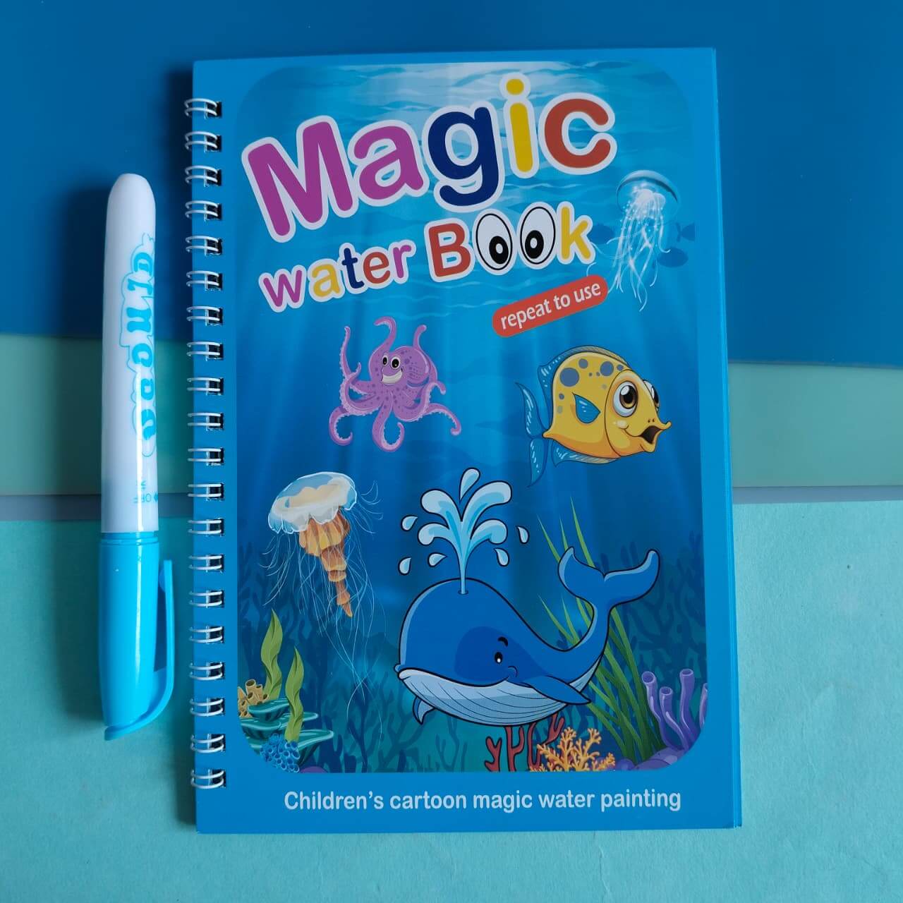 Children's magic water book with underwater illustrations and a marker on a blue background